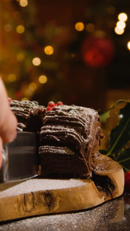 Vertical-Video-Of-At-Home-With-Food-And-Slice-Being-Cut-From-Traditional-Yule-Log-Dusted-With-Icing-Sugar